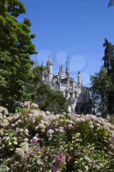 Quinta da Regaleira on  abright sunny day with blooming flowers in front.