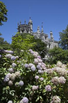 Quinta da Regaleira on a bright sunny day with blooming flowers in front.