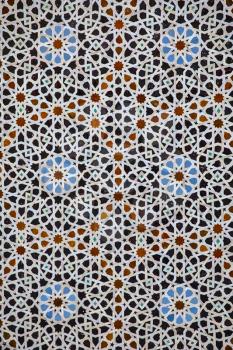 Traditional colorful geometrical patern of mosaic on the wall of islamic school Madrasa Bou Inania, Fez, Morocco.