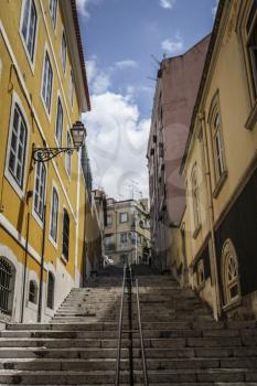 A street with stairs and colorful houses in iconic Barrio Alto a night life neighbourhood of Lisbon during the day.