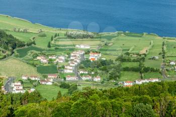 The blue waters of the Atlantic Ocean contrast with the green fields of Faial Island