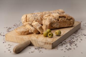 Baguette with olives and poppy seeds on a cutting desk