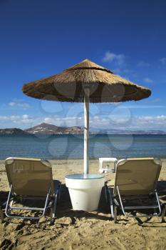 Sunbathing chairs and straw umbrella on St-Georges beach in Naxos, Greece