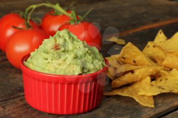 Guacamole dip with corn chips on rustic wooden table