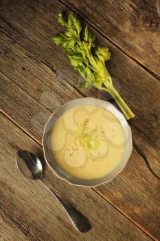Top view of a bowl of celery soup on a rustic background