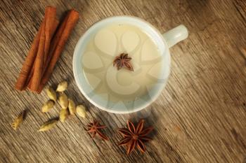 Top view of a chai tea with cinnamon, anise and cardamom on a wooden background