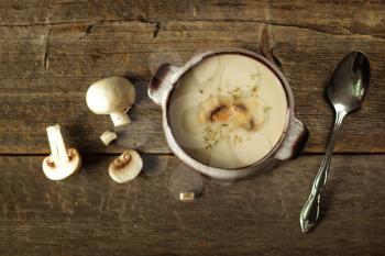 Mushroom soup  with spoon and fresh vegetables on a rustic background