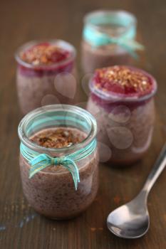 Healthy chocolate chia pudding with berry coulis on top with nuts and spoon on a wooden background