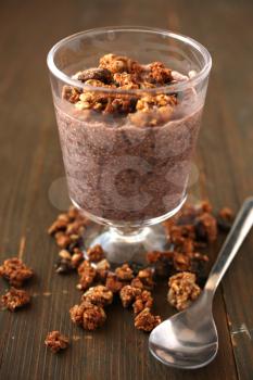 Healthy chocolate chia pudding with fresh nuts in a glass jar and spoon on a wooden background
