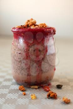 Healthy chocolate chia pudding with berry coulis on top and nuts