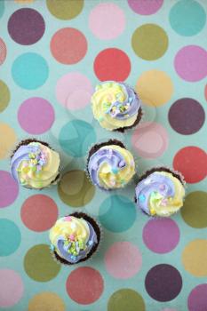 Easter yellow and lilac chocolate cupcake with candies on a colorful giant polka dots background