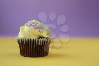  Easter yellow and lilac chocolate cupcake with candies on a yellow and purple background