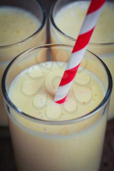 Three banana smoothies with a striped red straw 