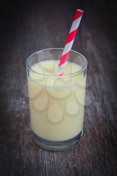 Banana smoothie with a striped red straw on a wooden table