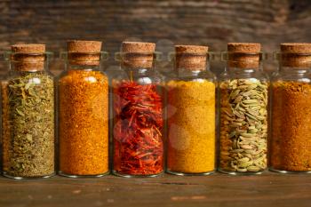 Spices, herbs and seeds for cooking in little jar in a row