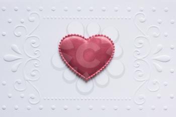 Blank embossed white paper with red satin hearts on it.  
