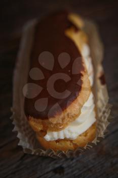 Chocolate eclair in a paper on a wooden surface