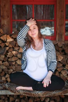 Smiling pregnant woman sitting on a bench in the countryside