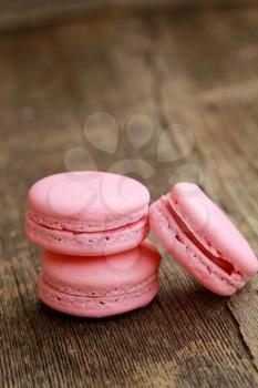 Three strawberry or raspberry macarons on a wooden table