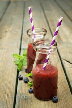 Blueberry smoothie freshly made in a jar with a lined straw

