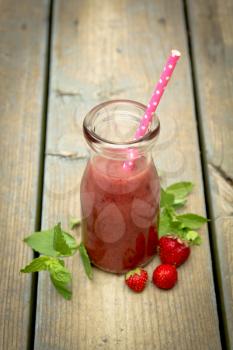 Top view of a strawberry smoothie with fresh fruits on a rustic wood