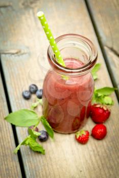 Top view of a berry smoothie with fresh fruits and mint on a rustic wood