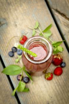 Top view of a berry smoothie with fresh fruits and mint on a rustic wood
