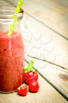 Half of strawberry smoothie with fresh fruits on a rustic wood