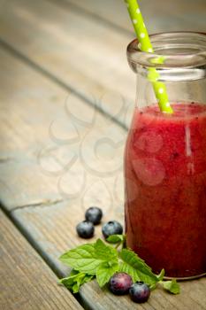 Half of blueberry smoothie with fresh fruits on a rustic wood