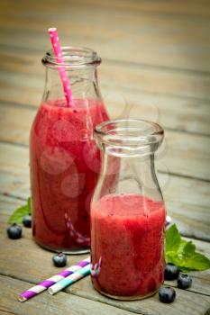 Blueberry smoothie with fresh fruits and straw on a rustic wood
