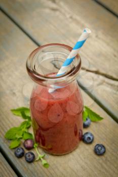 Top view of a blueberry smoothie with fresh fruits and mint on a rustic wood