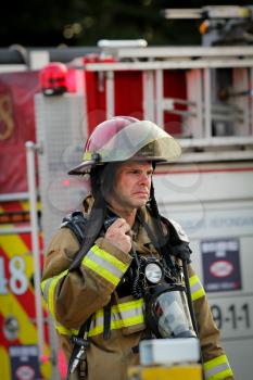 MONTREAL,  CANADA - AUGUST 01: Lieutenant fireman in front of firetruck on a fire site, talking on walkie on august 01, 2014 in MONTREAL