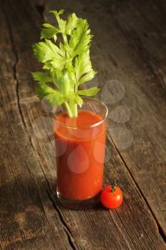 Tomato juice with celery branch on a wooden background