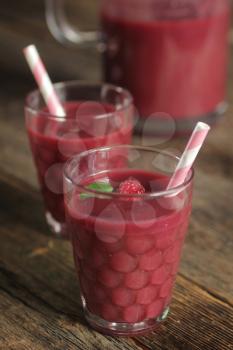 Raspberry smoothie with a pink straw on a rustic background