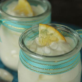 Lemon yogurt in a clear glass with turquoise ribbon and lemon on top