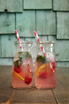 Two vintage bottles of pink lemonade with raspberry and mint standing on a wood background
