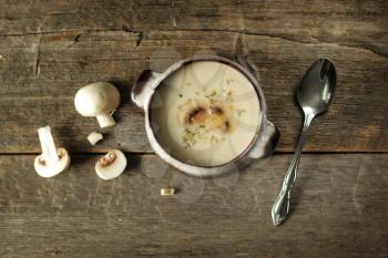 Mushroom soup  with spoon and fresh vegetables on a rustic background