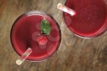 Top view of berry smoothies with a pink straw on a rustic background