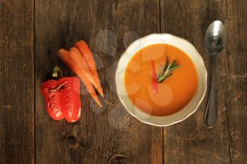 Carrot and grilled pepper soup on a wooden background
