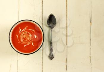 Tomato soup with spoon on a white wooden background