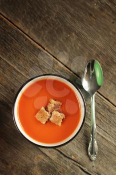 Tomato soup with spoon on a rustic background