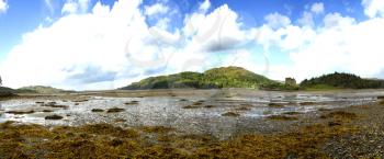 View of  Eilean Tioram in Loch Moidart at low tide with a cloudy and blue  sky in Highland, Scotland
