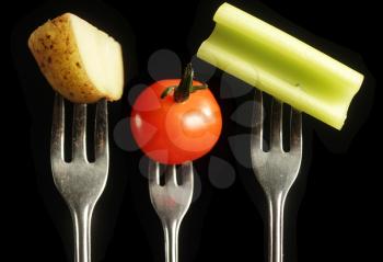 Potato, tomato and celery on a fork on a black background