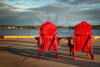 2 red Adirondack chairs in front of the ocean in Prince Edward island 