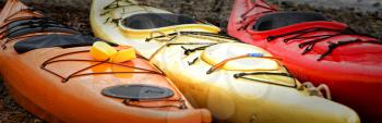 Orange, yellow and red kayak in a row ready to go on the sea