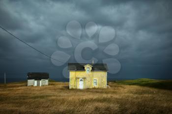 Old fisherman house with yellow tiles in a dark grey sky in iles de la madeleine in Canada