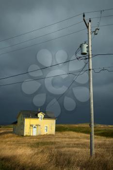 Old fisherman house with yellow tiles in a dark grey sky and a lamp post in iles de la madeleine in Canada