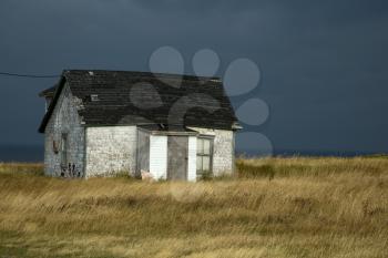 Old fisherman house with tiles in a dark grey sky in iles de la madeleine in Canada