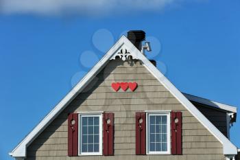 Detail of a beige rooftop with three red wooden hearts shape in Iles de la Madeleine in Canada