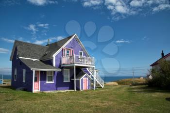 Purple house with pink windows against a blue sky in Iles de la Madeleine in Canada